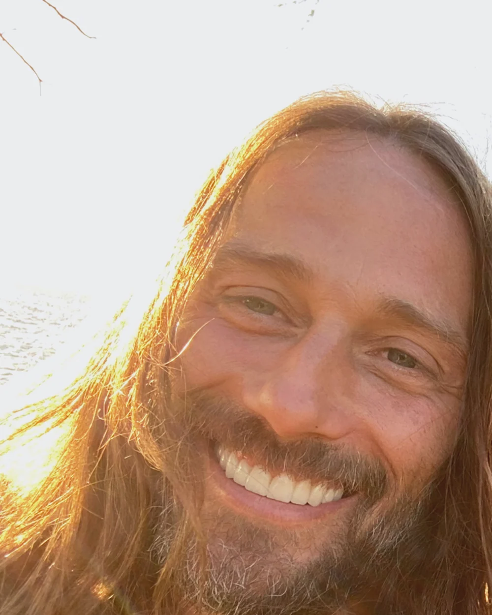 Michael “Karuna” Williams, founder of Symbiont Intelligence, outdoors in late afternoon light, smiling directly at the camera.